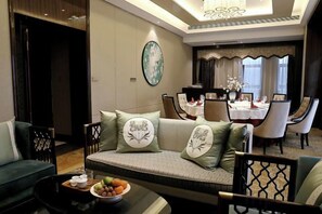 Une chambre d’hôtel équipée d’un canapé, d’une table à manger, de chaises et d’un lustre.