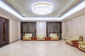 Un hall d’entrée spacieux, agrémenté d’un lustre, de deux rangées de canapés en cuir et d’un sol en marbre.