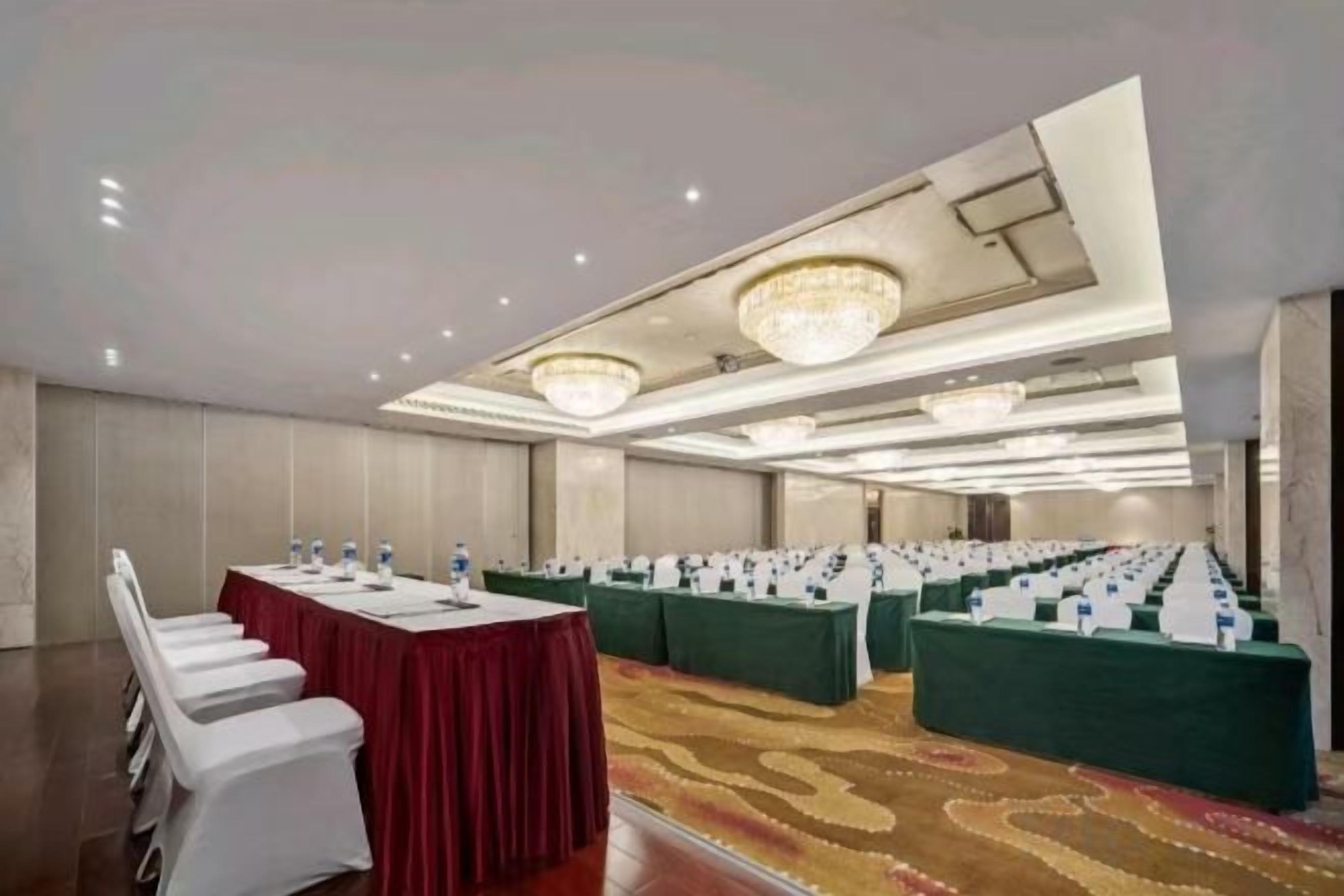 Un salón de conferencias con varias mesas, sillas y piso alfombrado.