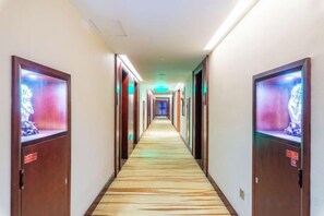 Un couloir d’hôtel avec des portes des deux côtés, chacune dotée d’un écran numérique.