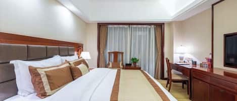 Une chambre d’hôtel avec un grand lit, un bureau, une chaise, une télévision et une fenêtre avec des rideaux.