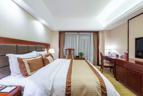 A hotel room with a large bed, a desk, a chair, a television, and a window with curtains. - Tianlong Hotel (Changsha)