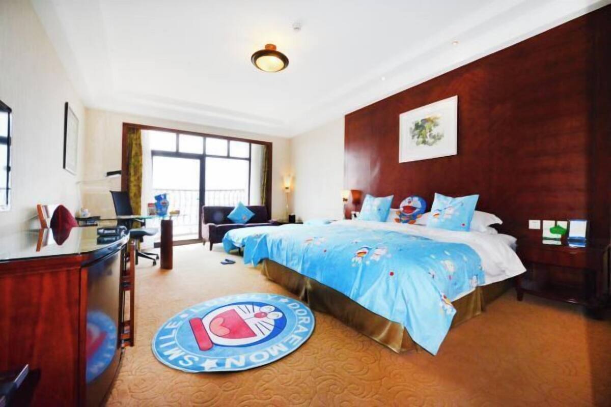 A hotel room with a large bed, a desk, and a view of the outside.