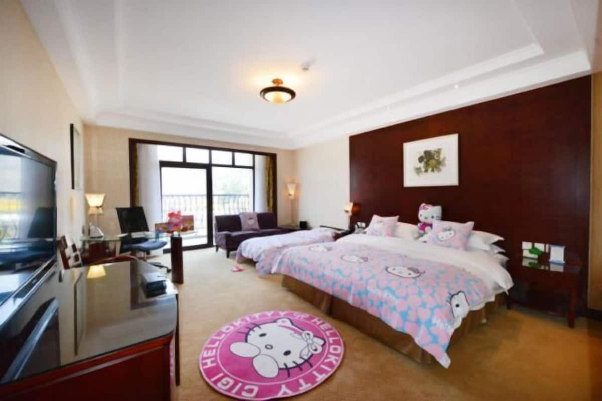 A hotel room with two beds, a TV, a desk, and a large window.