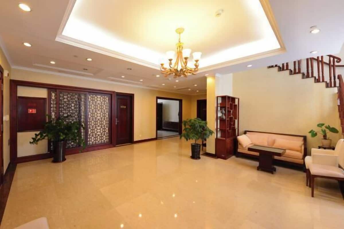 A spacious lobby with a chandelier, a sofa, and potted plants.