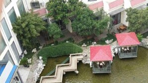 A courtyard with a small pond, steps leading down to the water, and two red-roofed structures. - Zhangjiagang Guomao Hotel (Suzhou)