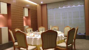 A conference room with a round table, six chairs, and a large window with blinds.