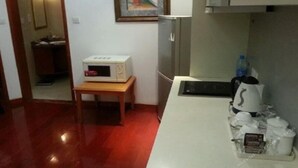 A compact kitchen with a microwave, a small table, and a coffee maker on the counter. - Zhangjiagang Guomao Hotel (Suzhou)