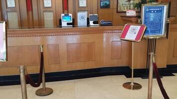 A reception desk with a wooden finish, a red velvet rope barrier, and a framed certificate on the wall.