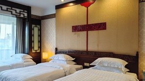 A hotel room with three beds, a decorative wall with a red accent, and a window with curtains. - Guilin Park Hotel (GUILIN)