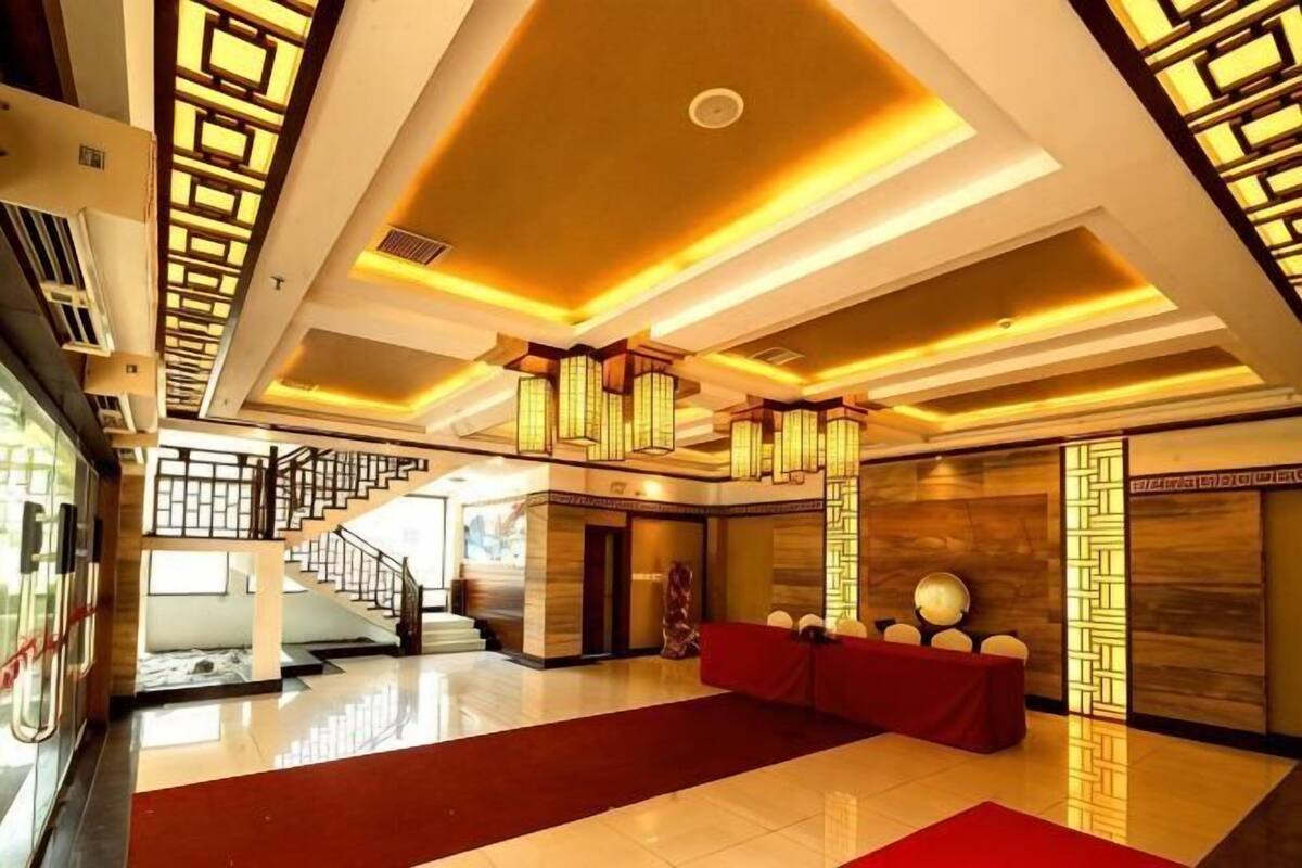 Un vestíbul d'hotel amb una escala, una recepció i una catifa vermella.