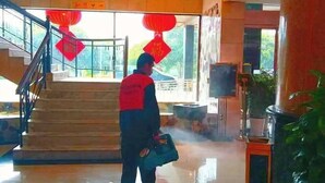 A person standing in a lobby with a staircase, red lanterns, and a large plant. - Guilin Park Hotel (GUILIN)