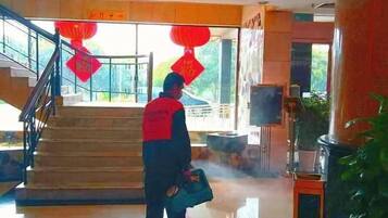 A person standing in a lobby with a staircase, red lanterns, and a large plant.