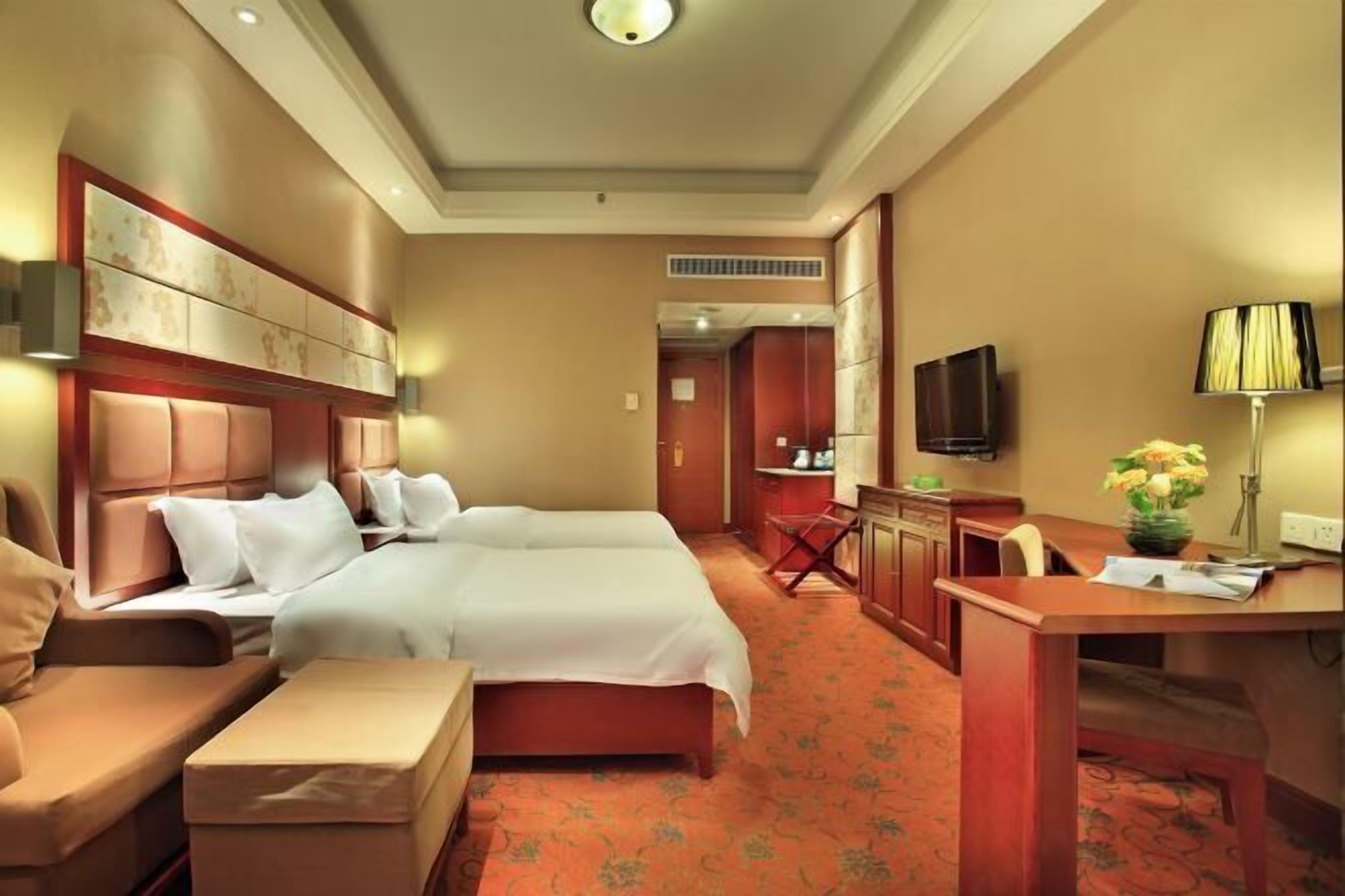 Une chambre d’hôtel avec un grand lit, un bureau, une chaise, un canapé et une télévision.