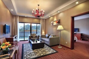 A modern hotel room with a large window, a chandelier, a sofa, a coffee table, and a lamp. - Guilin Park Hotel (GUILIN)