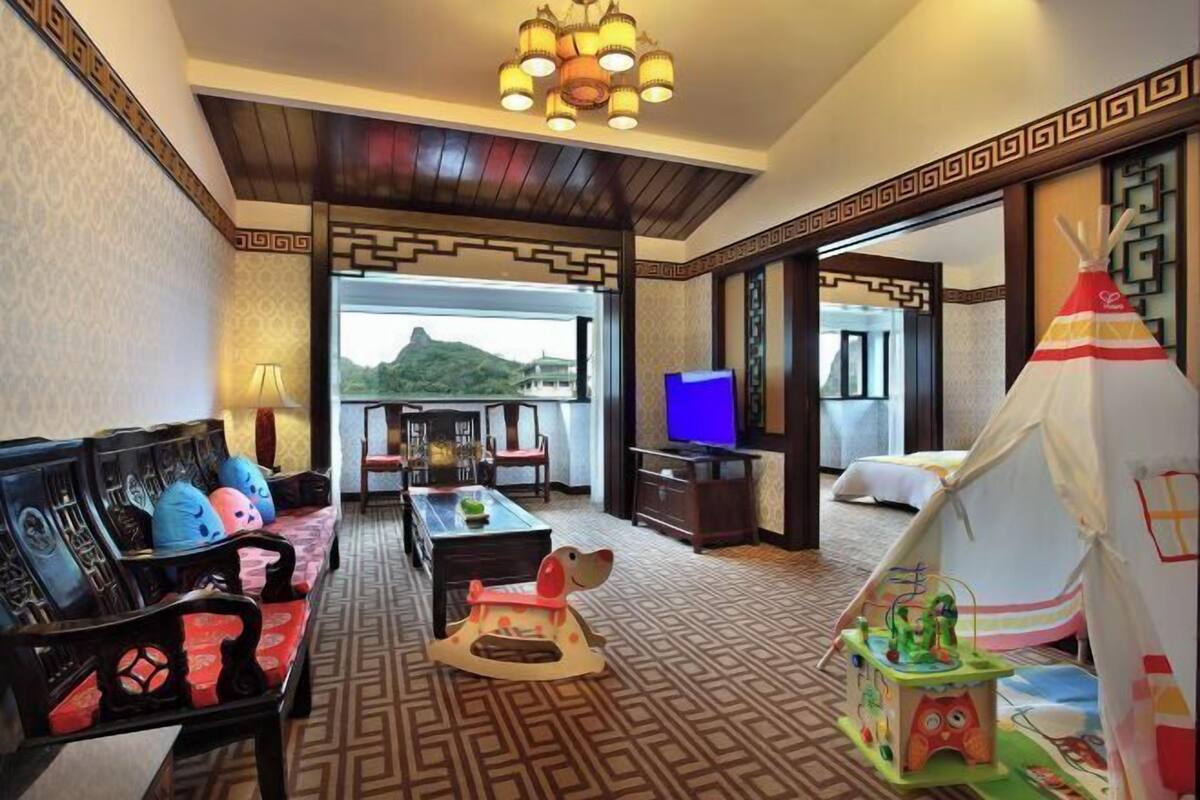 Habitació d'hotel amb un sofà tradicional, televisió, taula de dinar i una estructura semblant a una tenda.