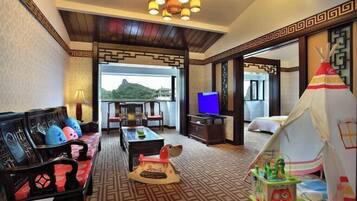 A hotel room with a traditional sofa, a television, a dining table, and a tent-like structure.