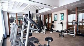 A gym with exercise equipment, mirrors, and a large window. - Metropolitan Hotel (DONGGUAN)