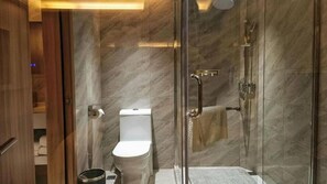 A modern bathroom with a glass shower enclosure, a toilet, and a bidet. - Metropolitan Hotel (DONGGUAN)