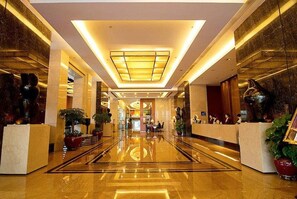 A spacious hotel lobby with a reflective floor, a central light fixture, and decorative sculptures. - Metropolitan Hotel (DONGGUAN)