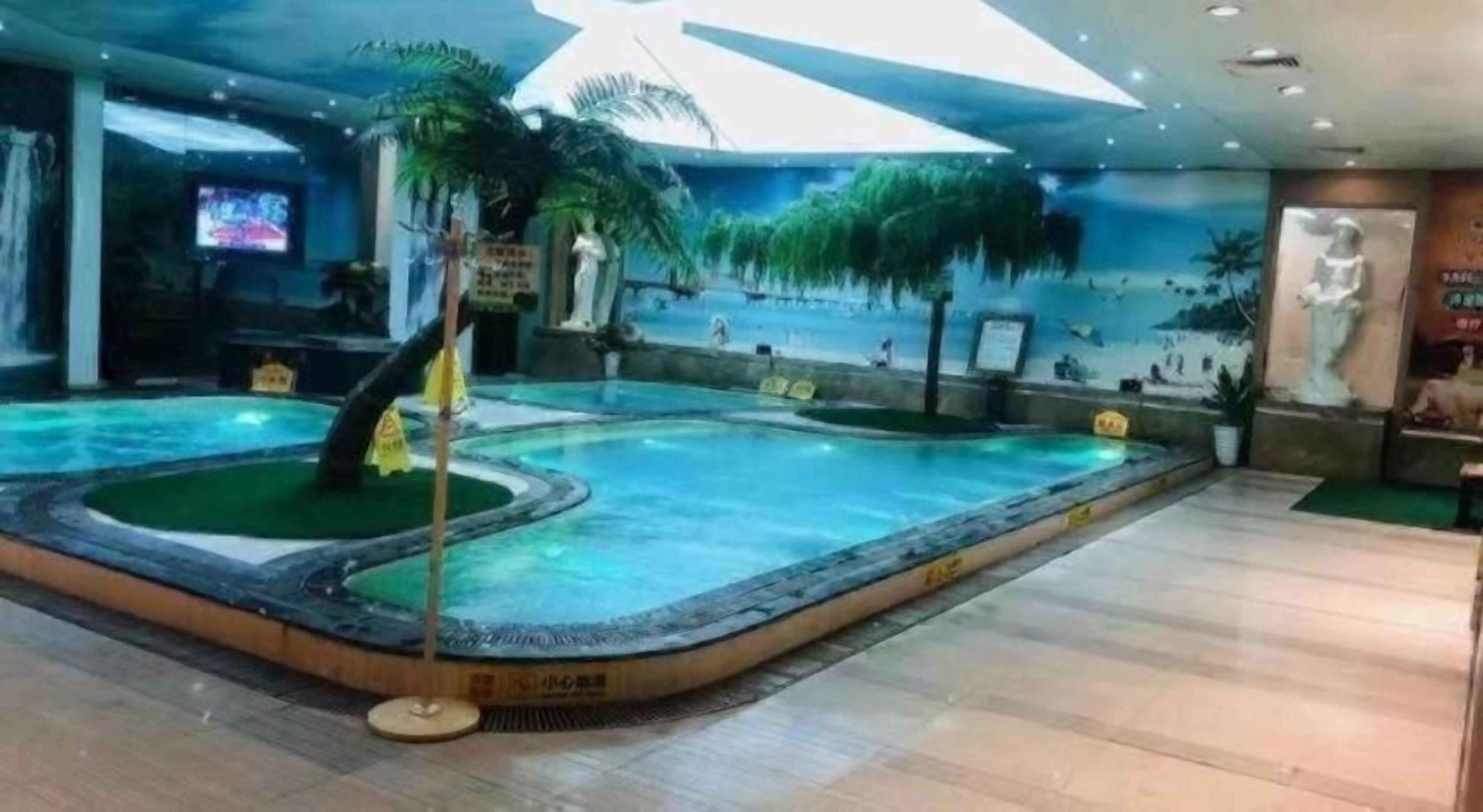 An indoor swimming pool with a tropical theme, including palm trees and a mural.