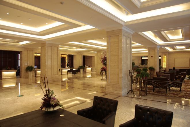 A spacious lobby with a reception desk, seating area, and decorative plants.