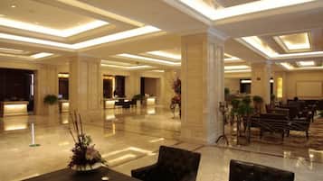 A spacious lobby with a reception desk, seating area, and decorative plants.