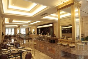 Un amplio vestíbulo de hotel con un mostrador de recepción de mármol, varias zonas de estar y grandes ventanales que dejan entrar luz natural.