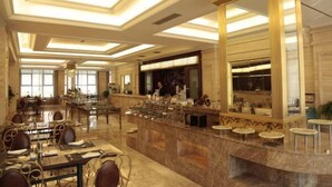 Een ruime hotellobby met een marmeren receptiebalie, zitgedeeltes en grote ramen die natuurlijk licht binnenlaten.