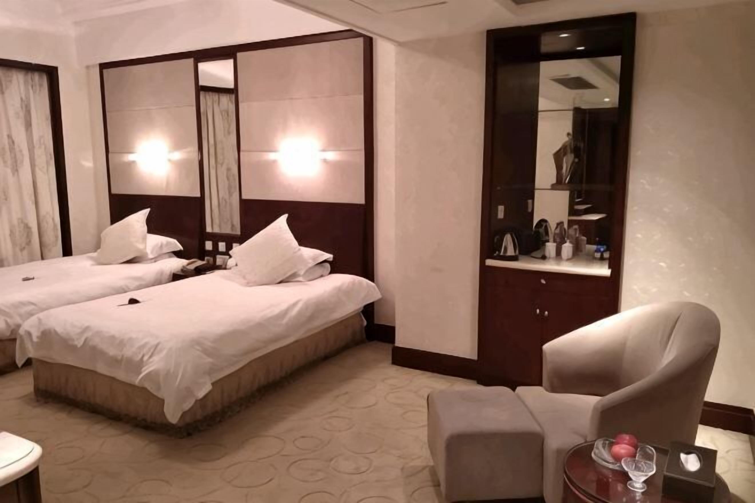 Une chambre d’hôtel avec deux lits, une chaise, une petite table et un miroir.