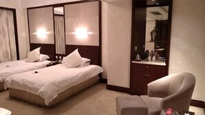 Een hotelkamer met twee bedden, een stoel, een tafeltje en een spiegel.