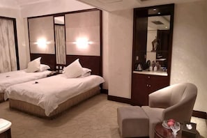 A hotel room with two beds, a chair, a small table, and a mirror. - Kaiyuan International Hotel (Jiaxing)