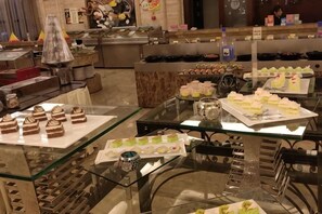 Ett område med ett buffébord där olika sorters desserter och bakverk presenteras på glasbord.