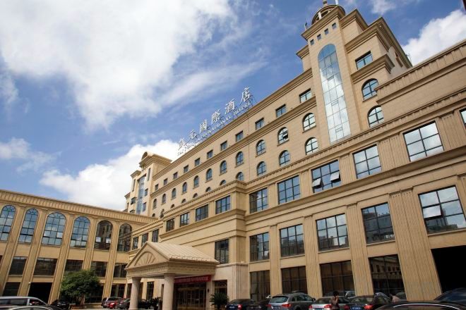 A large hotel building with multiple floors, a prominent entrance, and a clear sky.