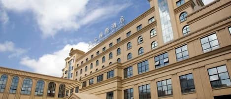 Un gran edificio de hotel con varios pisos, una entrada destacada y un cielo despejado.