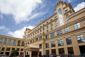 Un gran edificio de hotel con varios pisos, una entrada destacada y un cielo despejado.