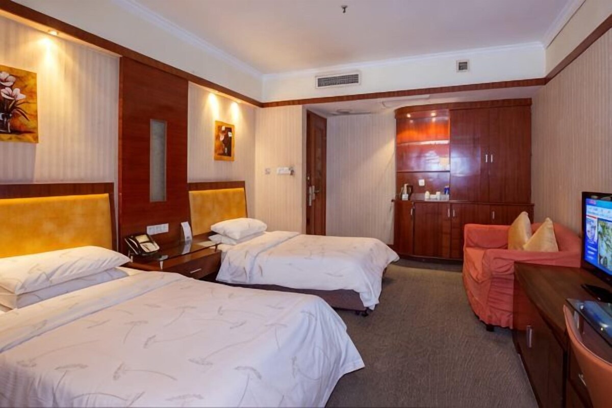 Habitación de hotel con dos camas, un escritorio con teléfono, televisión y armario.