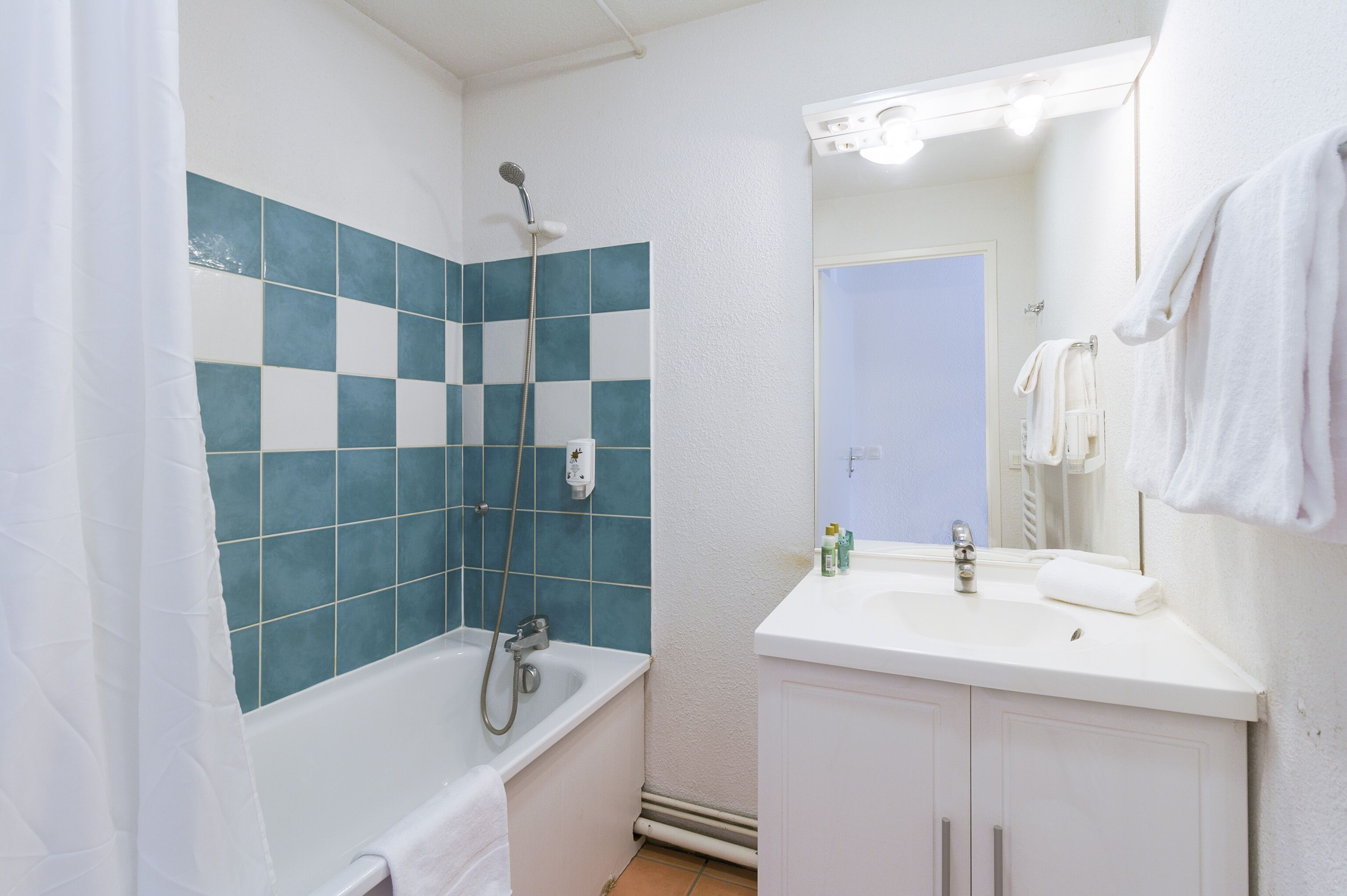 A bathroom with a bathtub, a sink, and a mirror.