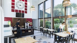 Ein Café mit einer großen Uhr, Holztischen und einer Theke mit einer Kaffeemaschine.