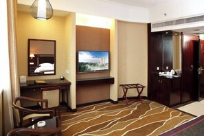 A hotel room with a desk, chair, television, wardrobe, and a patterned carpet. - Celeste Palace Hotel (Jiangmen)