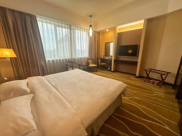Une chambre d’hôtel avec un grand lit, un bureau, une chaise, une télévision et une lampe.