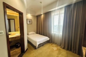 A hotel room with a bed, a bathroom with a mirror, and a window with curtains. - Celeste Palace Hotel (Jiangmen)