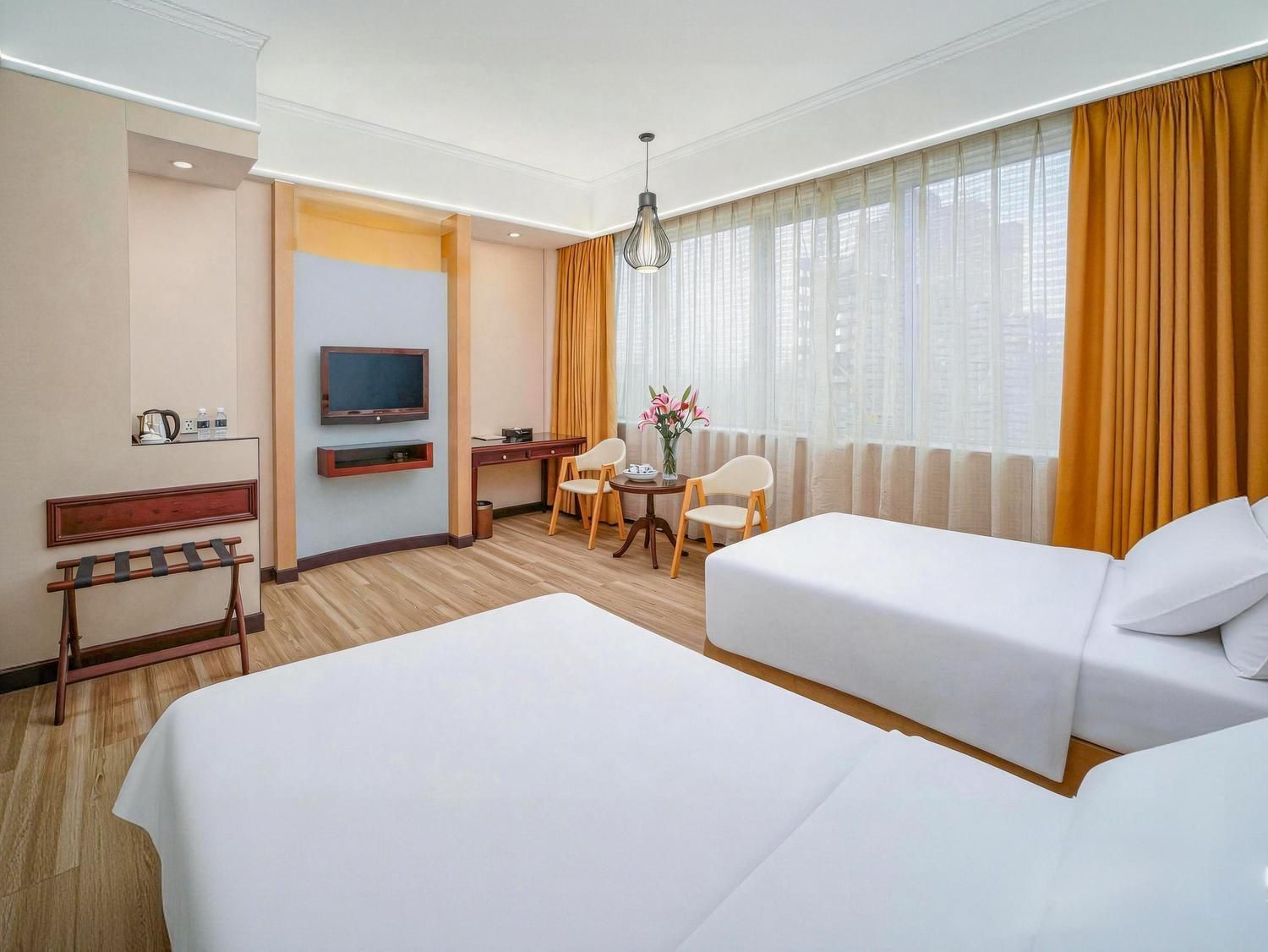 A hotel room with two beds, a desk, a chair, a TV, and a window with curtains.