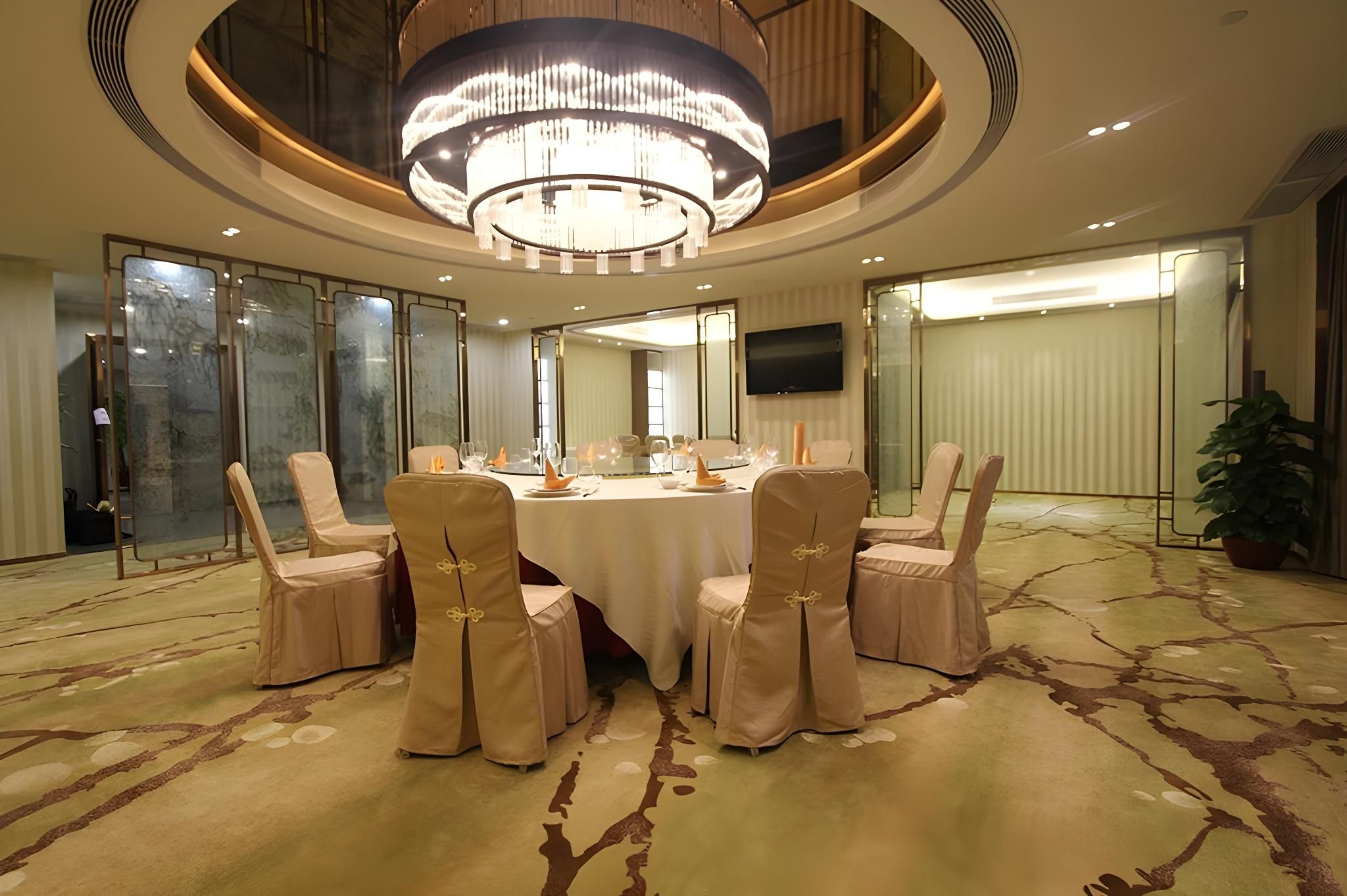 A conference room with a round table, six chairs, and a large chandelier.
