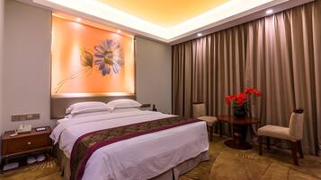 A hotel room with a bed, bedside table, lamp, chair, and a large window with curtains.