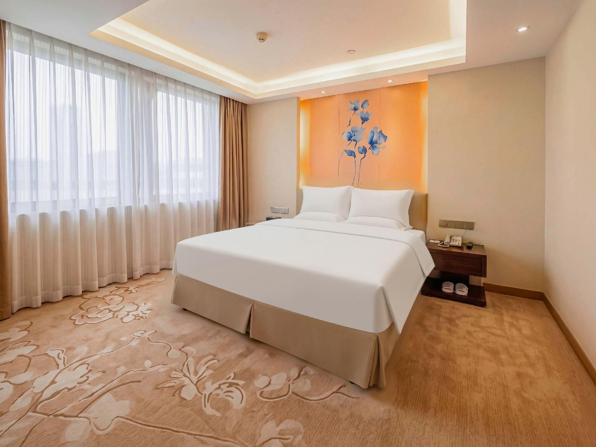 Ein Hotelzimmer mit einem großen Bett, einem Nachttisch, einem Telefon und einer Wandleuchte.
