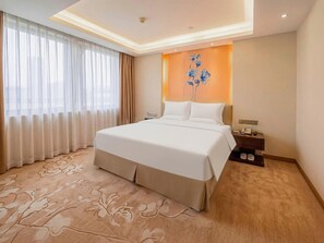 A hotel room with a large bed, a nightstand, a telephone, and a wall-mounted light fixture. - Celeste Palace Hotel (Jiangmen)
