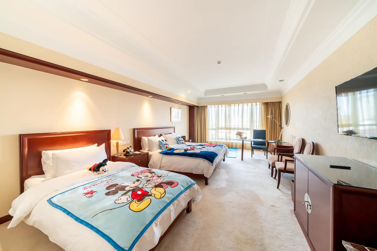 Une chambre d’hôtel avec deux lits, un bureau et une télévision.