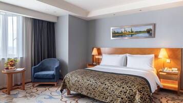 Una habitación de hotel con cama, una silla, una mesita de noche, una lámpara, un cuadro en la pared y una ventana con cortinas.
