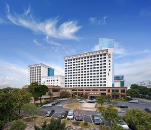 A hotel with multiple buildings, a parking lot, and surrounding greenery. - Maritim Hotel Taicang Garden (Suzhou)